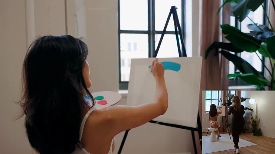 Isabella painting during a boudoir film shoot with the camera operator visible in an inset